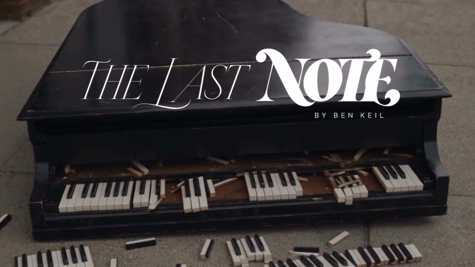 The Last Note title card over a broken grand piano lying on a pavement, keys scattered around it, in the short film by Ben Keil