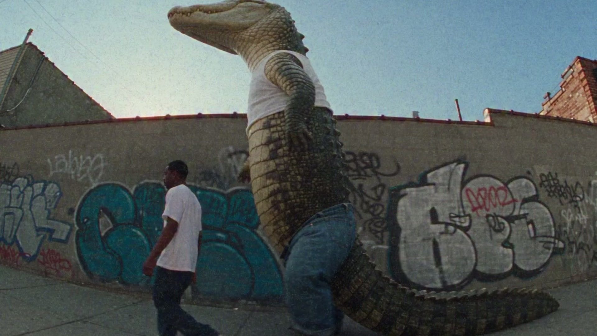 An enormous upright alligator in a white T-shirt and jeans walks past a man on a graffiti-lined city street in My Brain Is Broken by Kobala